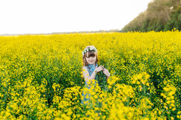Fototapeta premium A young girl walks the yellow field