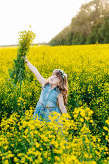 Fototapeta premium A young girl walks the yellow field
