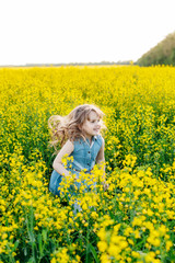 Naklejka na ściany i meble A young girl walks the yellow field