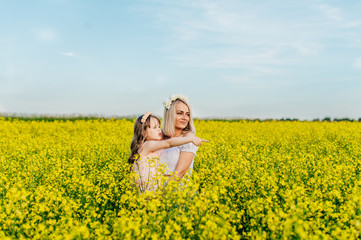 Fototapeta premium Mom and child having fun in a yellow flowering field