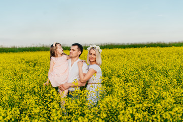 Fototapeta premium Family dad, mom and baby in the yellow field at sunset