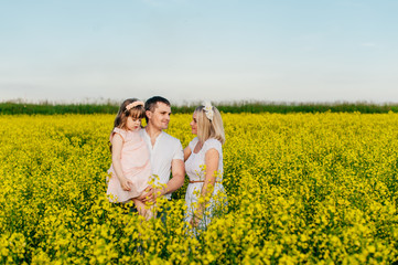 Fototapeta premium Family dad, mom and baby in the yellow field at sunset