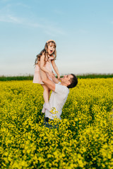 Man with child in a yellow field at sunset