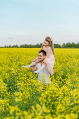 Fototapeta premium Man with child in a yellow field at sunset