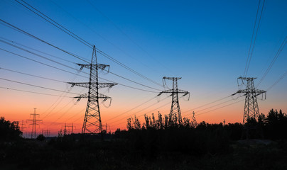 Fototapeta premium High-voltage power lines during fiery sunrise