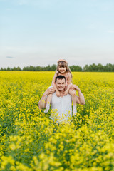 Man with child in a yellow field at sunset