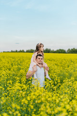 Fototapeta premium Man with child in a yellow field at sunset