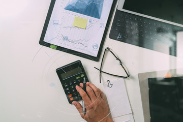 top view of businessman hand working with finances about cost and calculator and latop with mobile phone on withe desk in modern office