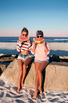 Happy girls eating watermelon on the beach. Friendship, happiness, beach, summer concept.