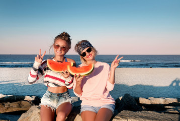 Happy girls eating watermelon on the beach. Friendship, happiness, beach, summer concept.