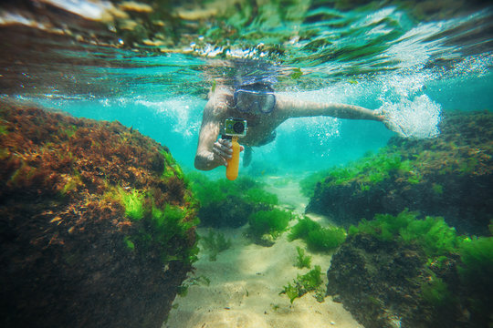 Young man, swimming underwater and making photos