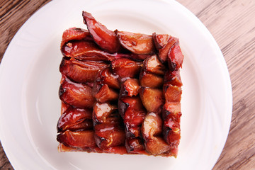 rustic plum cake on wooden background with plums around