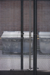 Private Abfallcontainer  / Abfallcontainer stehen hinter einem Gitterzaun in einem verschließbaren Außenplatz.