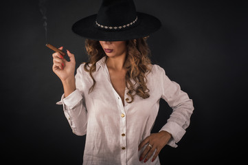 Portrait of sexy elegant lady woman with hat smoking cigar