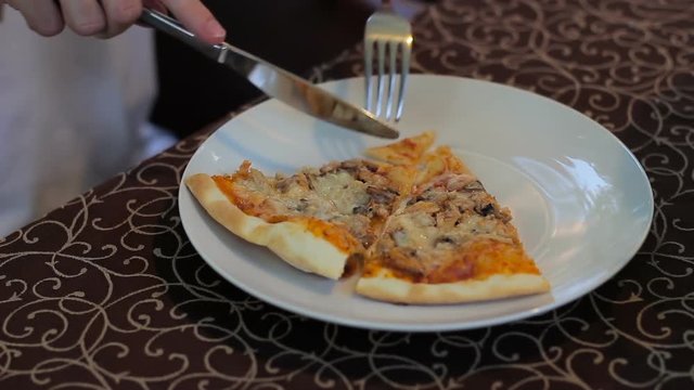 Male hands cutting pizza on a plate