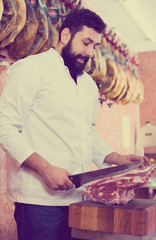 Male shop assistant carving meat