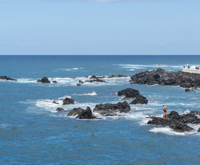 Mann auf einem Felsen im Meer