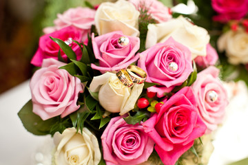 Wedding bouquet white and pink roses with golden rings.