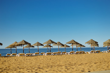 Sunny sky and chairs with parasol on the beautiful beach of Portugal