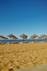 Sunny sky and chairs with parasol on the beautiful beach of Portugal