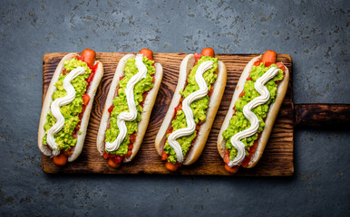 Chilean Completo Italiano. Hot dog sandwiches with tomato, avocado and mayonnaise on wooden board....