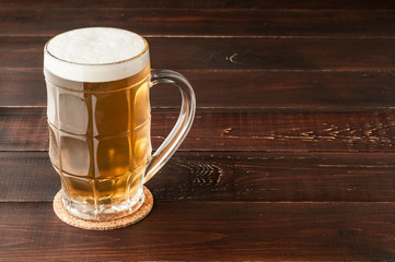 glass of cold frothy lager beer and potato chips plate on wooden table