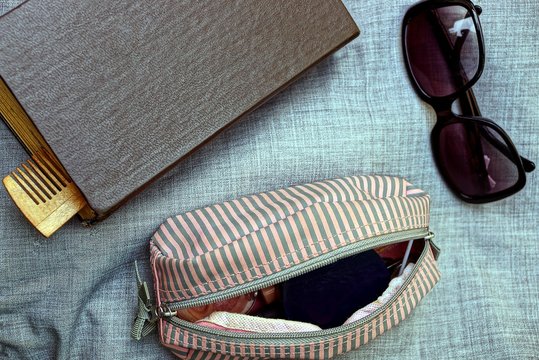 книга и солнцезащитные очки с открытой сумкой на серой материи