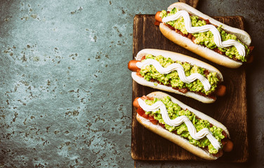 Chilean Completo Italiano. Hot dog sandwiches with tomato, avocado and mayonnaise on wooden board....