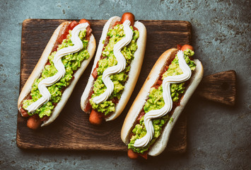 Chilean Completo Italiano. Hot dog sandwiches with tomato, avocado and mayonnaise on wooden board....