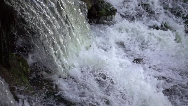 Powerful waterfall in slow motion. Water flows and falls creating splashes and foam. Power and beauty in nature.