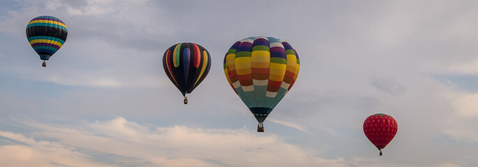 Fototapeta premium Colorful array of hot air balloons float through the sky at dusk for banner
