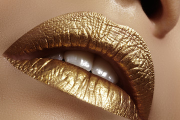Beautiful closeup with female plump lips with gold color makeup. Fashion celebrate make-up, glitter cosmetic