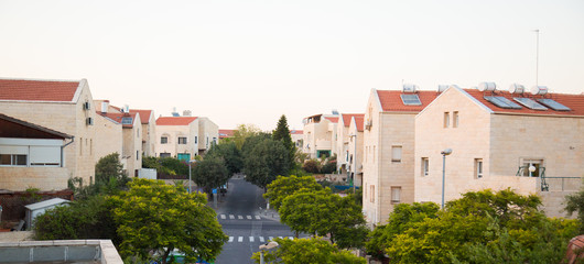 The construction of a new district in Jerusalem. The appearance of the city in the desert. Typical houses on background of mountains in Jerusalem, Israel. Solar panels on the roofs of houses