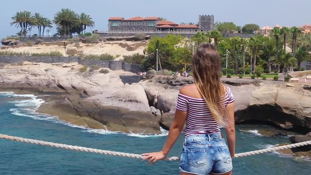 Tenerife. Spain.  Beautiful blond girl on vacation observes Playa de Las Americas, near Fanabe beach. With Casa del Duque view. Las Americas is the one of the most popular holiday resort..