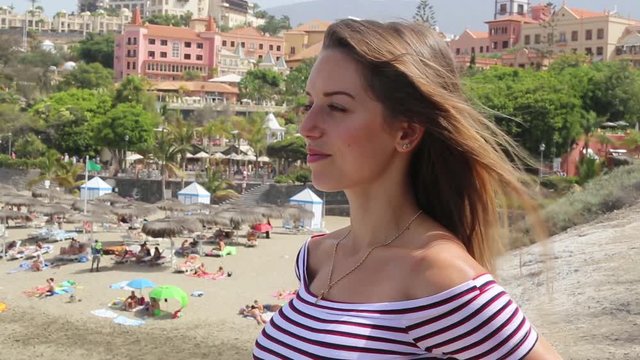 Tenerife. Spain. Beautiful blond girl on vacation observes Del Duque beach (Playa del Duque) located in Costa Adeje in South of Tenerife island in Las Americas..