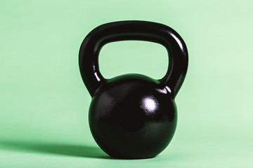 Obraz na płótnie Canvas Black cast iron kettlebell on a green background
