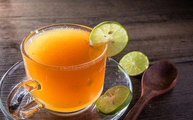 Honey bees and Lemon juice in crystal glass Drinking to relieve sore throat And healthy with wooden spoon on wooden background.