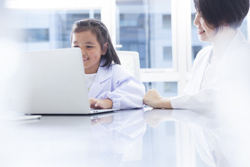 The teacher and the girl are studying with a laptop computer