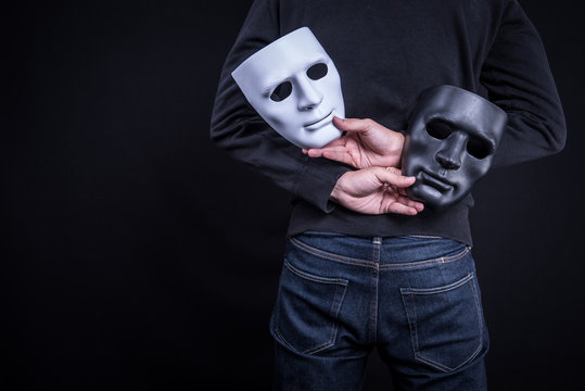 Mystery man holding black and white mask. Anonymous social masking concept.