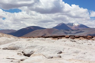 Fototapeta na wymiar Colorful landscape with volcanic mountain snow peak under cloudy sky. Salt flats, red rocks and volcanic mountains of San Pedro de Atacama, Chile, South America.