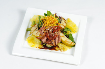 Salad with meat vegetables and fruits in a square plate on a white background apples pears pineapples