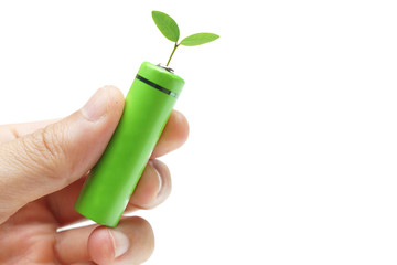 Hand holding a green rechargeable aa battery with a green small plant - Using  environmentally...