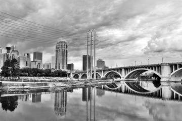 Cloudy morning in Minneapolis. Minneapolis downtown skyline and Third Avenue Bridge above Saint Anthony Falls, Mississippi river in black and white, Midwest USA, Minnesota state.
