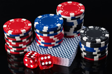 deck of cards and poker chips with cubes on a dark reflective background