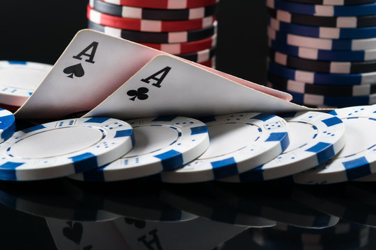 Two aces of playing cards lie on chips for playing poker on a dark background