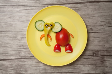 Elephant made of raw food on plate and wooden desk