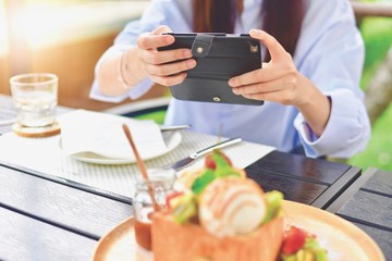 Hand Holding a Smartphone While Taking a Photo of Desserts