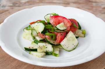Salad of red tomatoes and cucumbers on a white plate