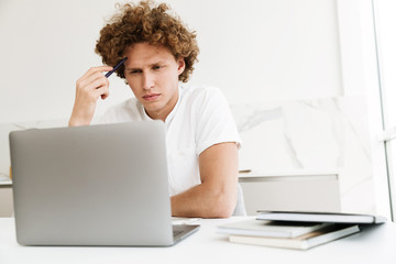 Handsome concentrated serious man using laptop computer.