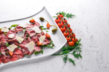 Carpaccio with meat and vegetables. Italian cuisine. On a wooden background. Top view. Free space for your text.